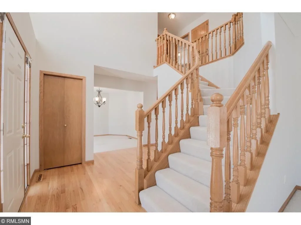 White painted foyer and staircase with natural wood railings, balusters, and trim