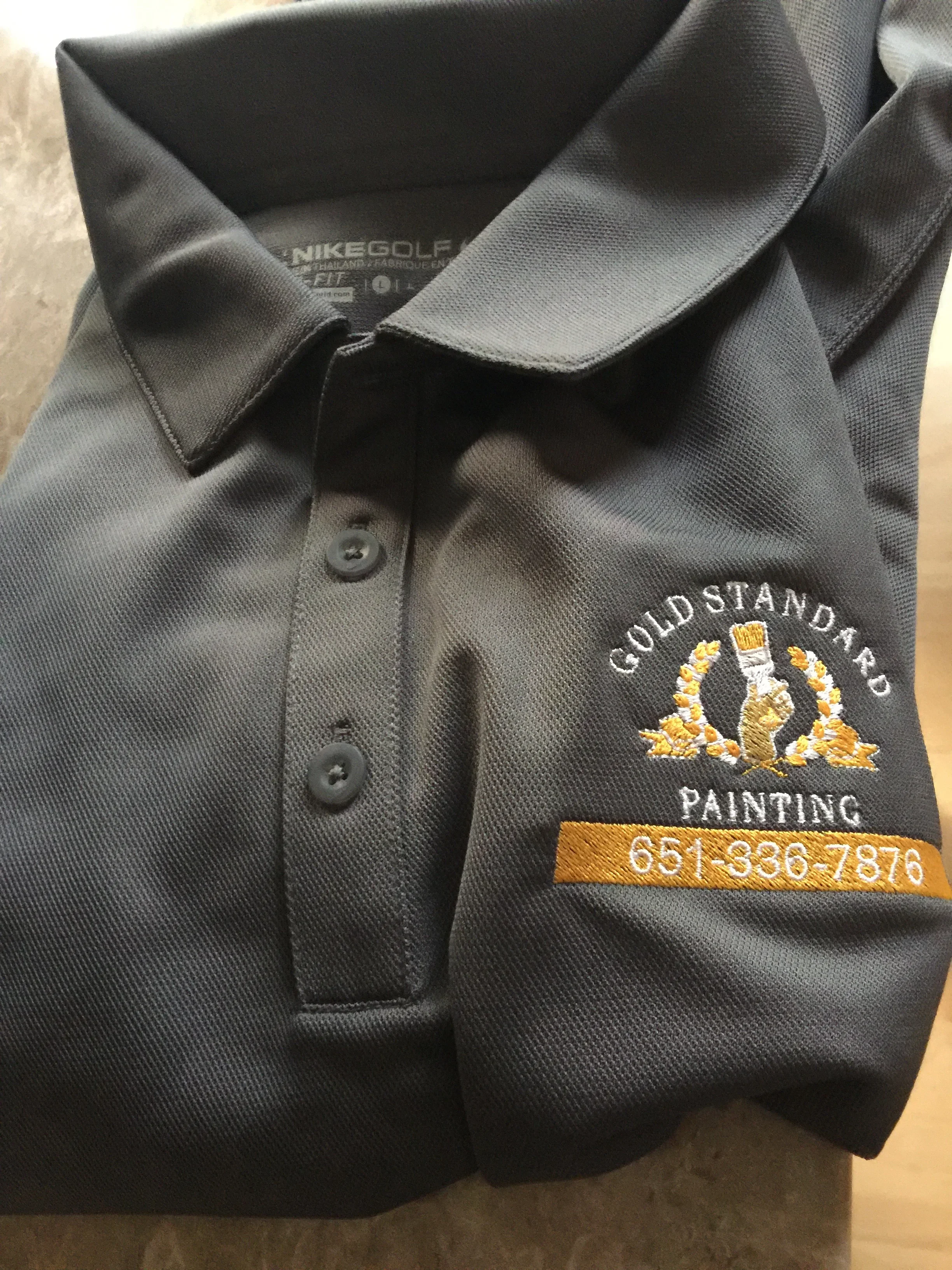 Charcoal polo shirt with gold and white embroidered logo and business details on chest