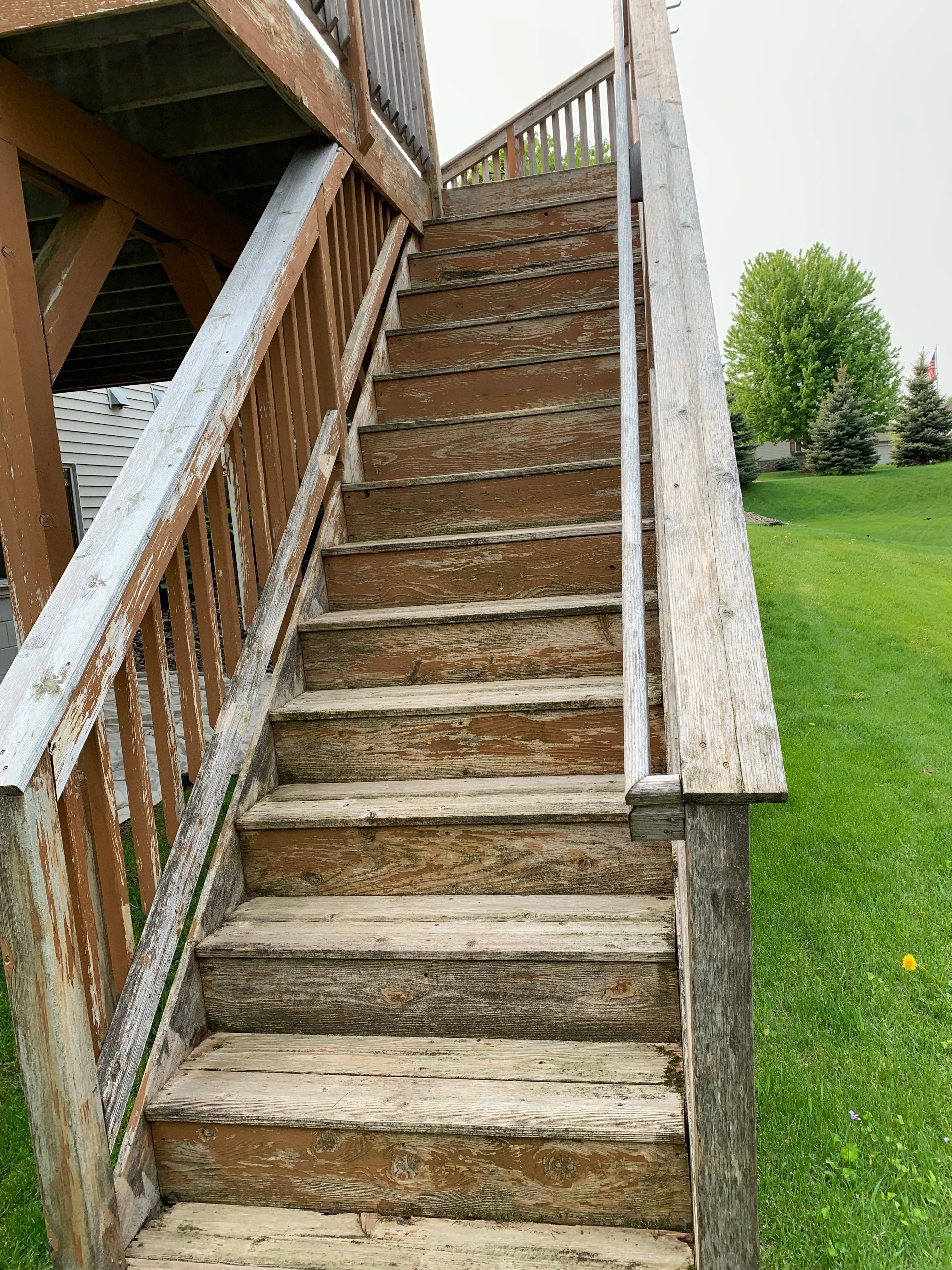 Wooden exterior staircase with restored treads, railings, and posts leading to upper deck