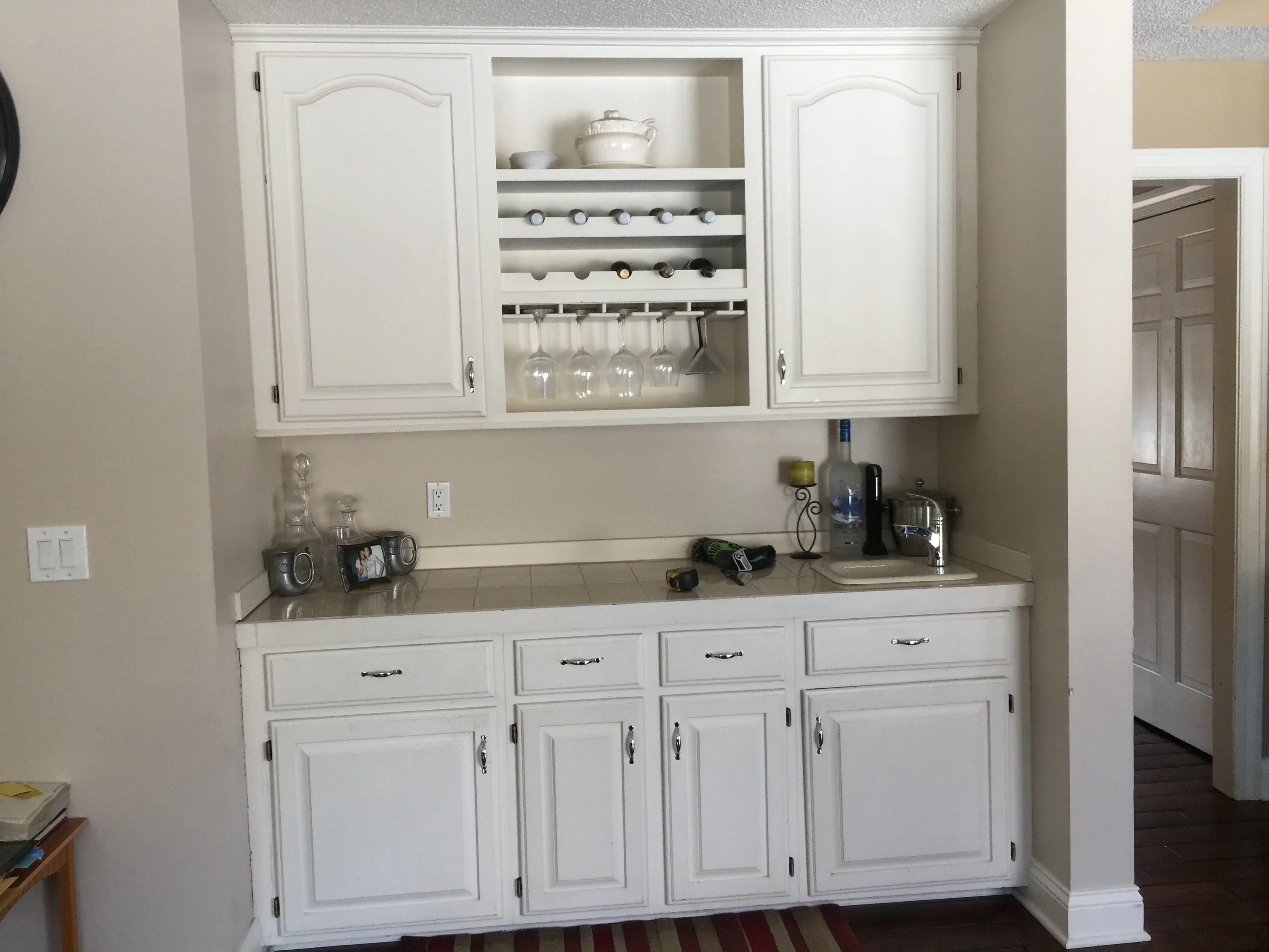 White painted kitchen cabinets with open shelving, wine racks, and glass holders above countertop