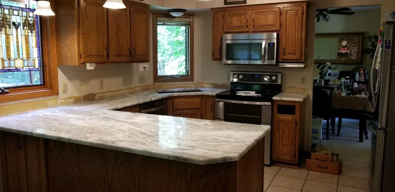 Wood kitchen cabinets with marble countertops, stainless steel appliances, and painted walls