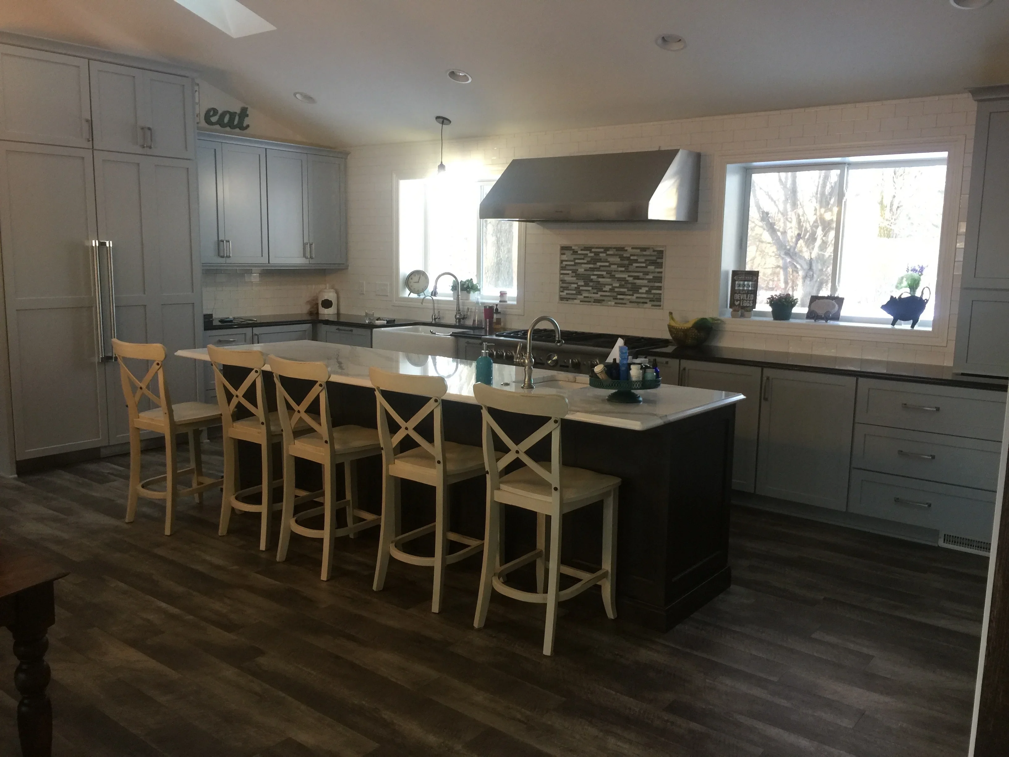 Gray painted kitchen cabinets, white trim, painted ceiling, and island with light wood bar seating