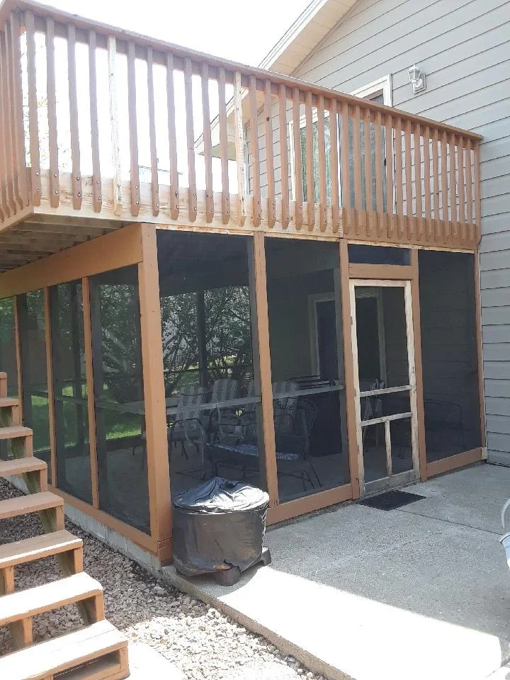 Wooden deck with vertical railings and screened porch enclosure with stained wood framing and black screens