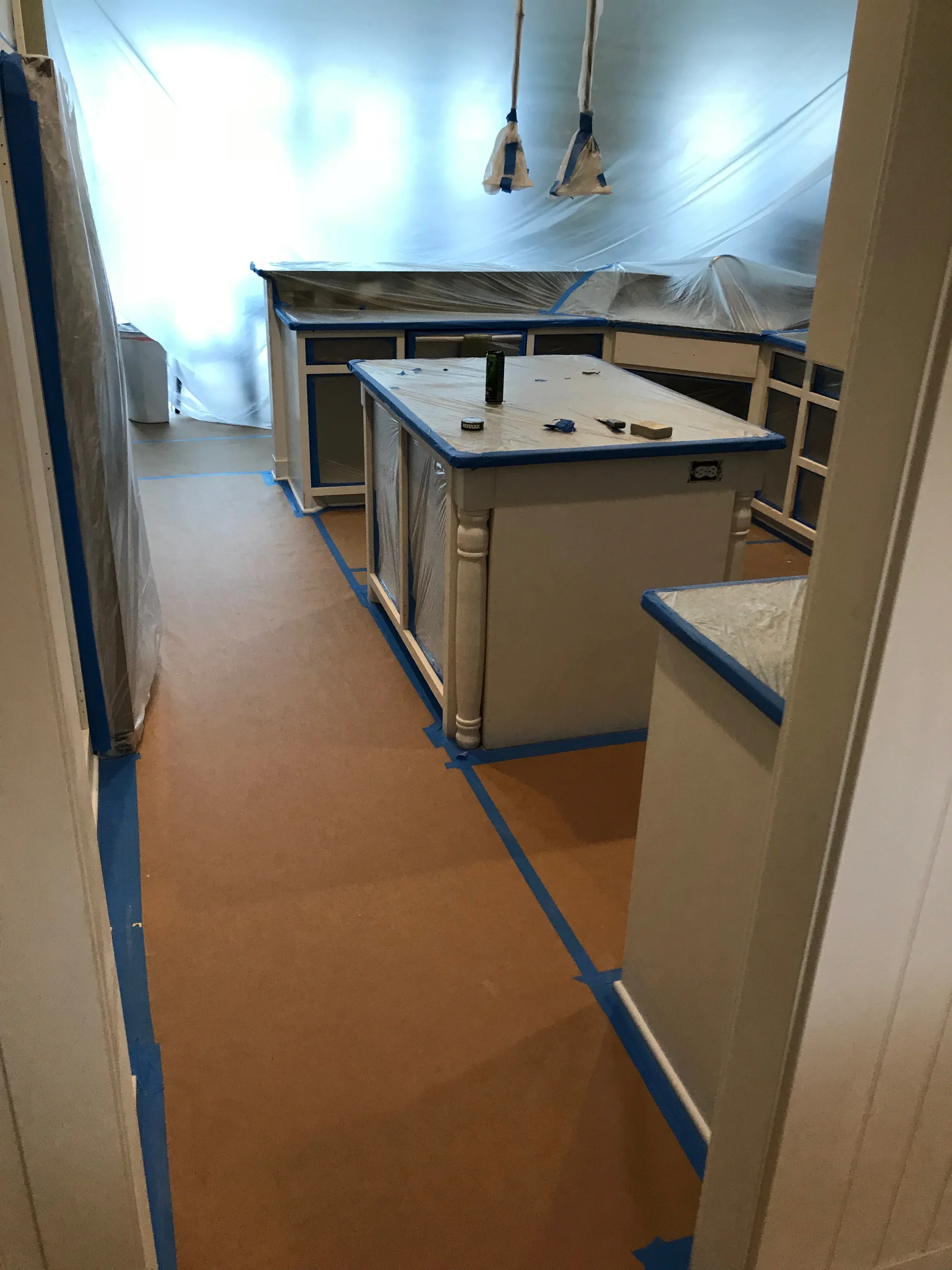 Kitchen cabinets masked with plastic and blue painter's tape for interior painting project
