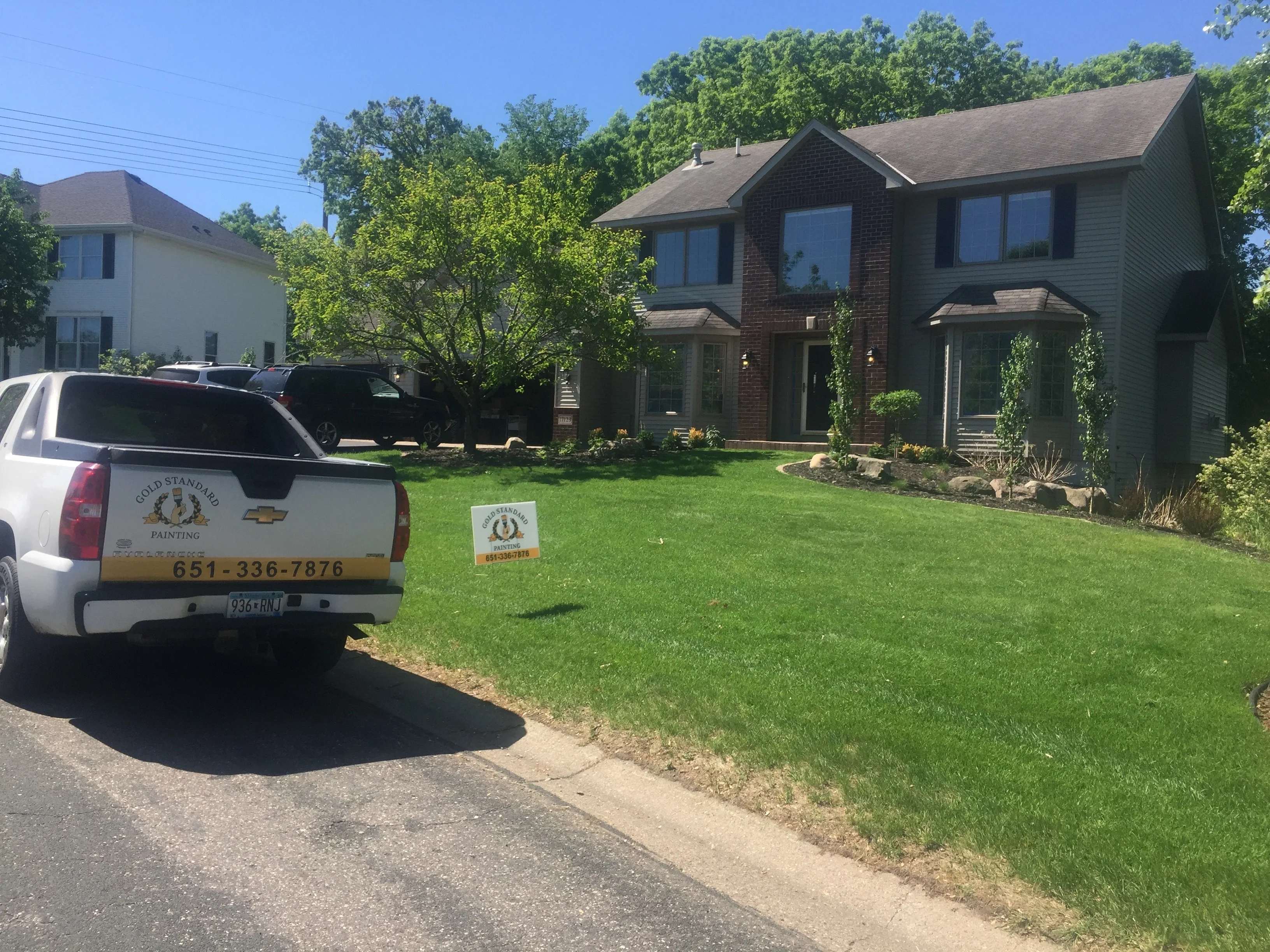 Two-story brick home with freshly painted exterior, large windows, and manicured lawn