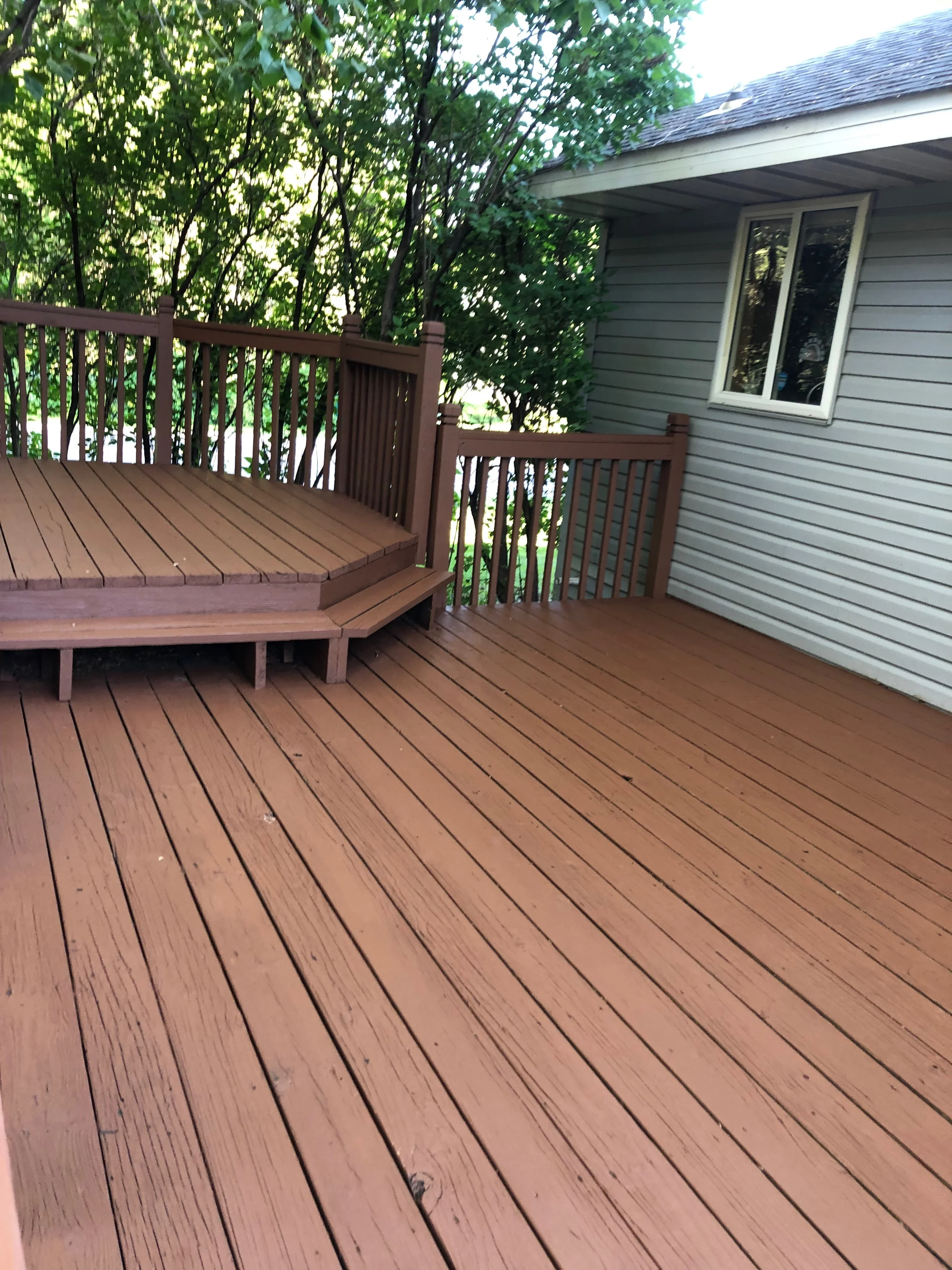 Warm brown stained composite deck with built-in bench seating and vertical railing balusters