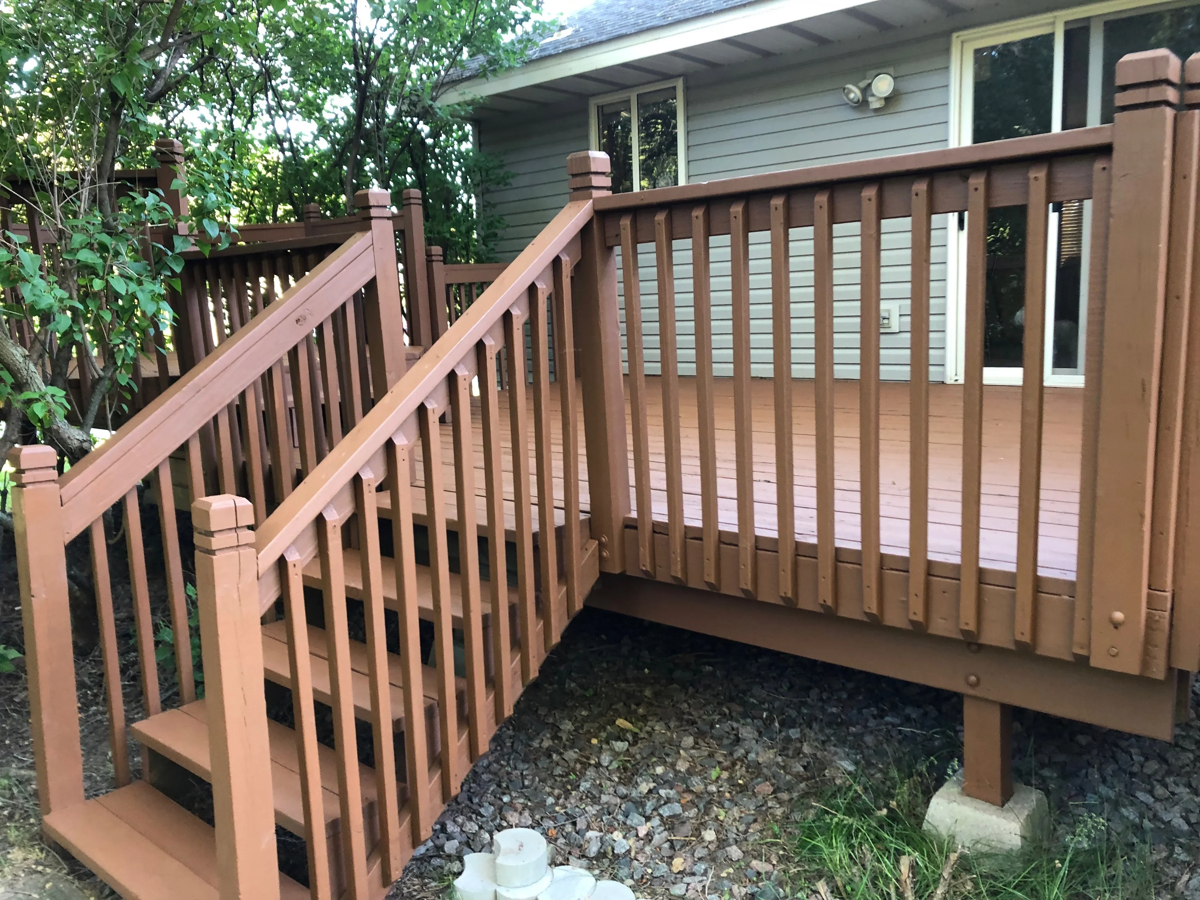 Composite deck with stairs, railings, and balusters attached to residential home