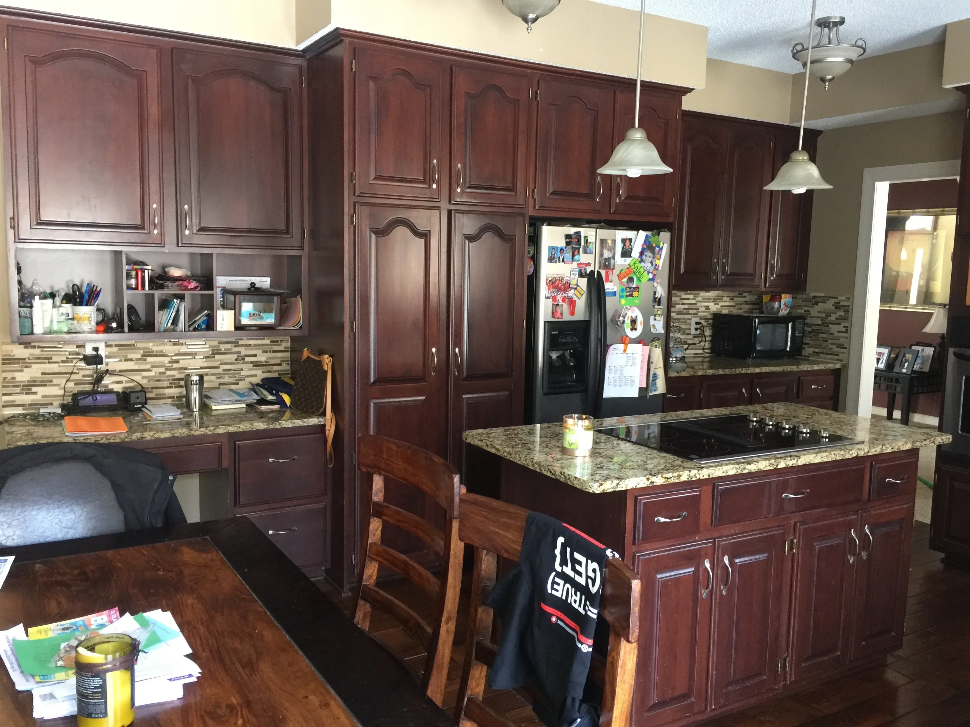 Cherry-stained kitchen cabinets with mosaic tile backsplash and granite countertops