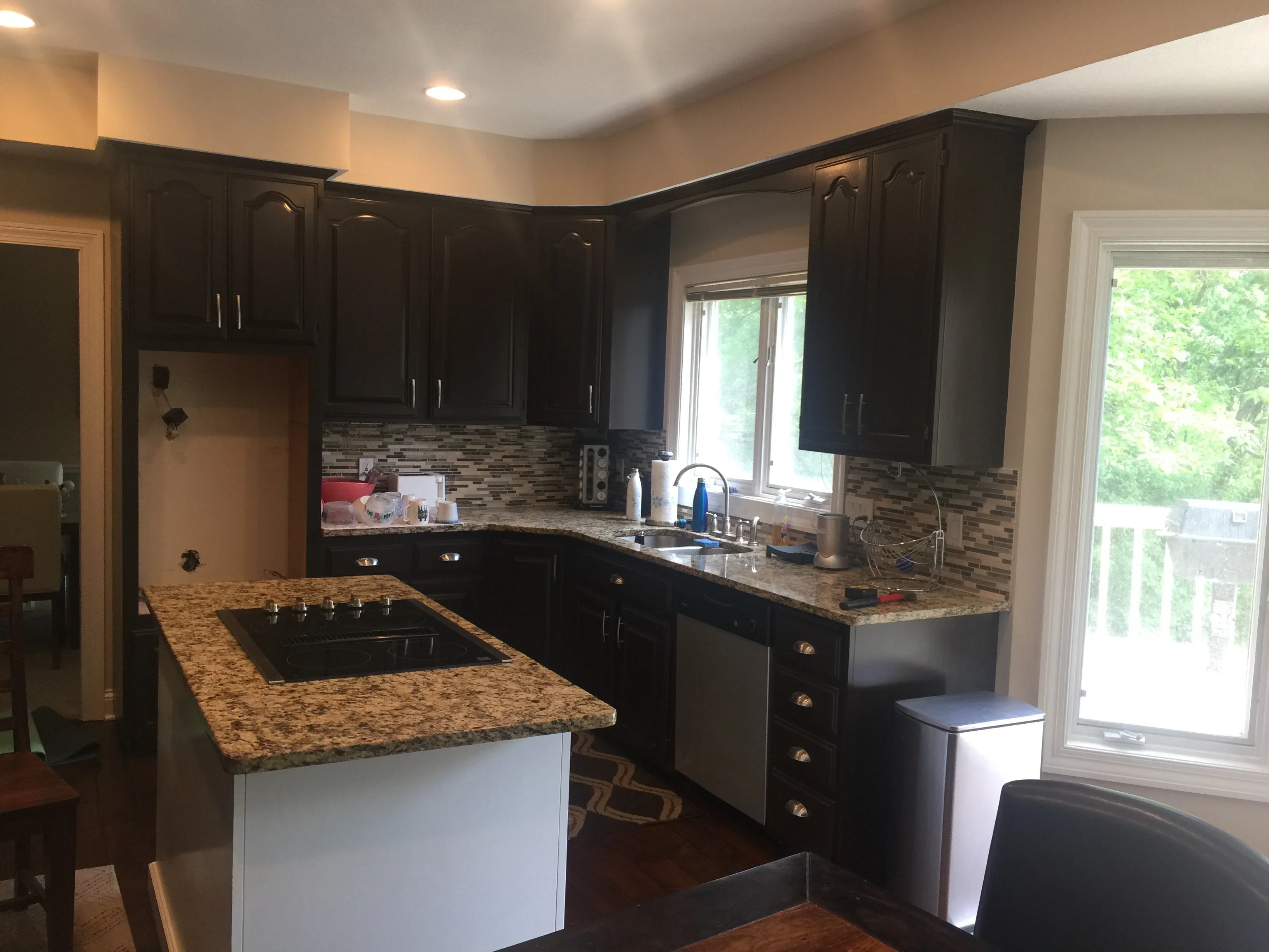 Black painted kitchen cabinets with granite countertops, beige walls, and recessed lighting