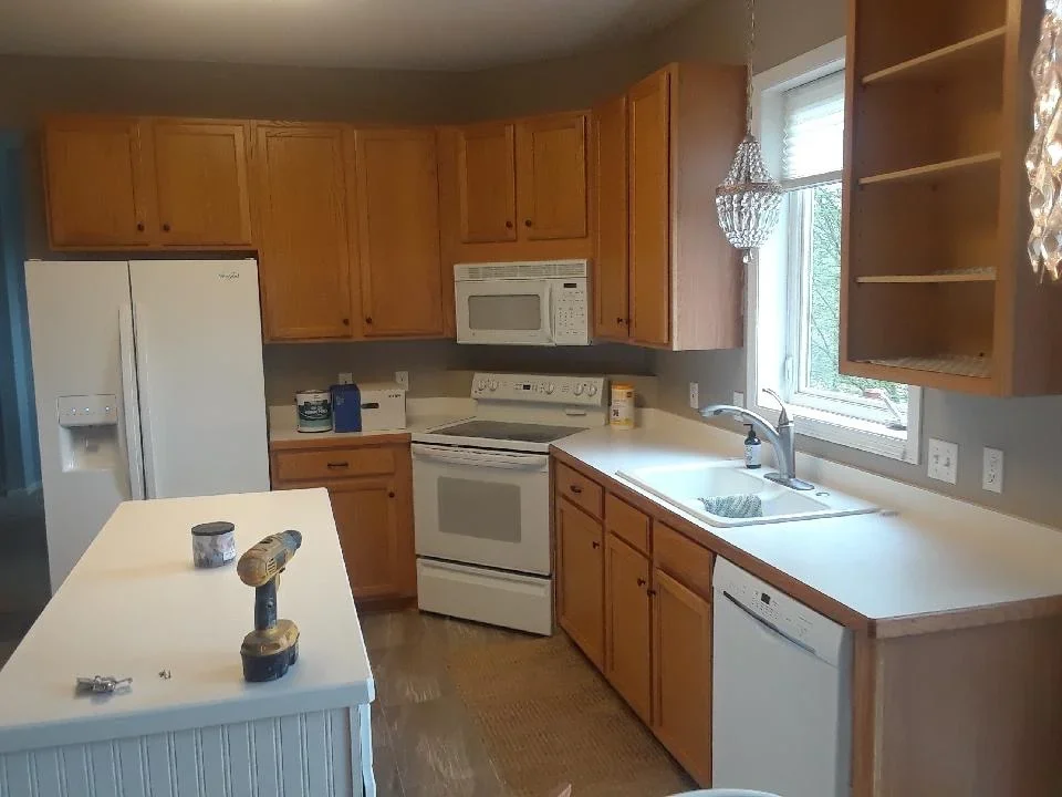 Honey-stained wood kitchen cabinets with white countertops and stainless steel appliances
