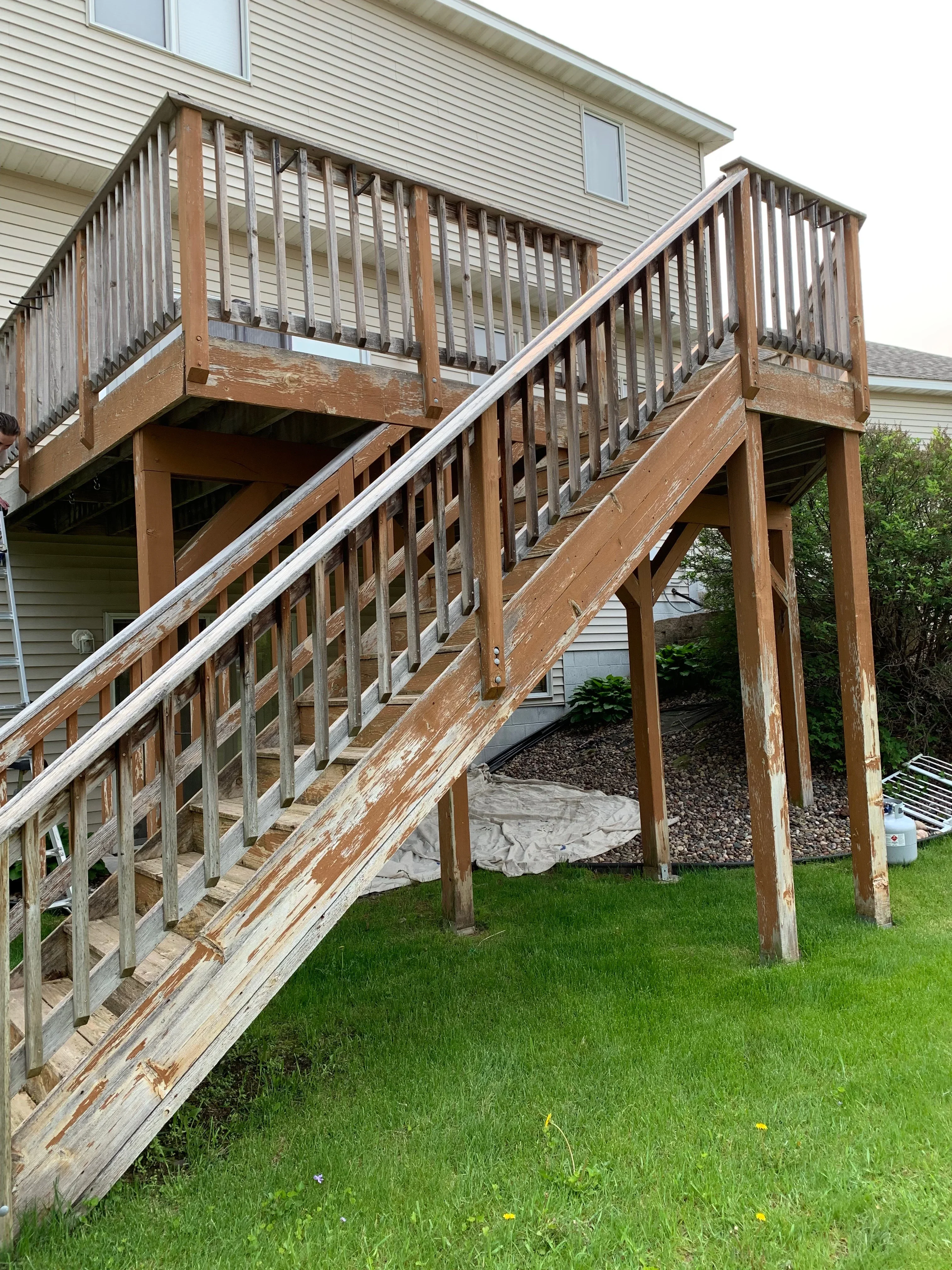 Wooden deck with stained railings, posts, and boards showing restoration work on multi-level structure