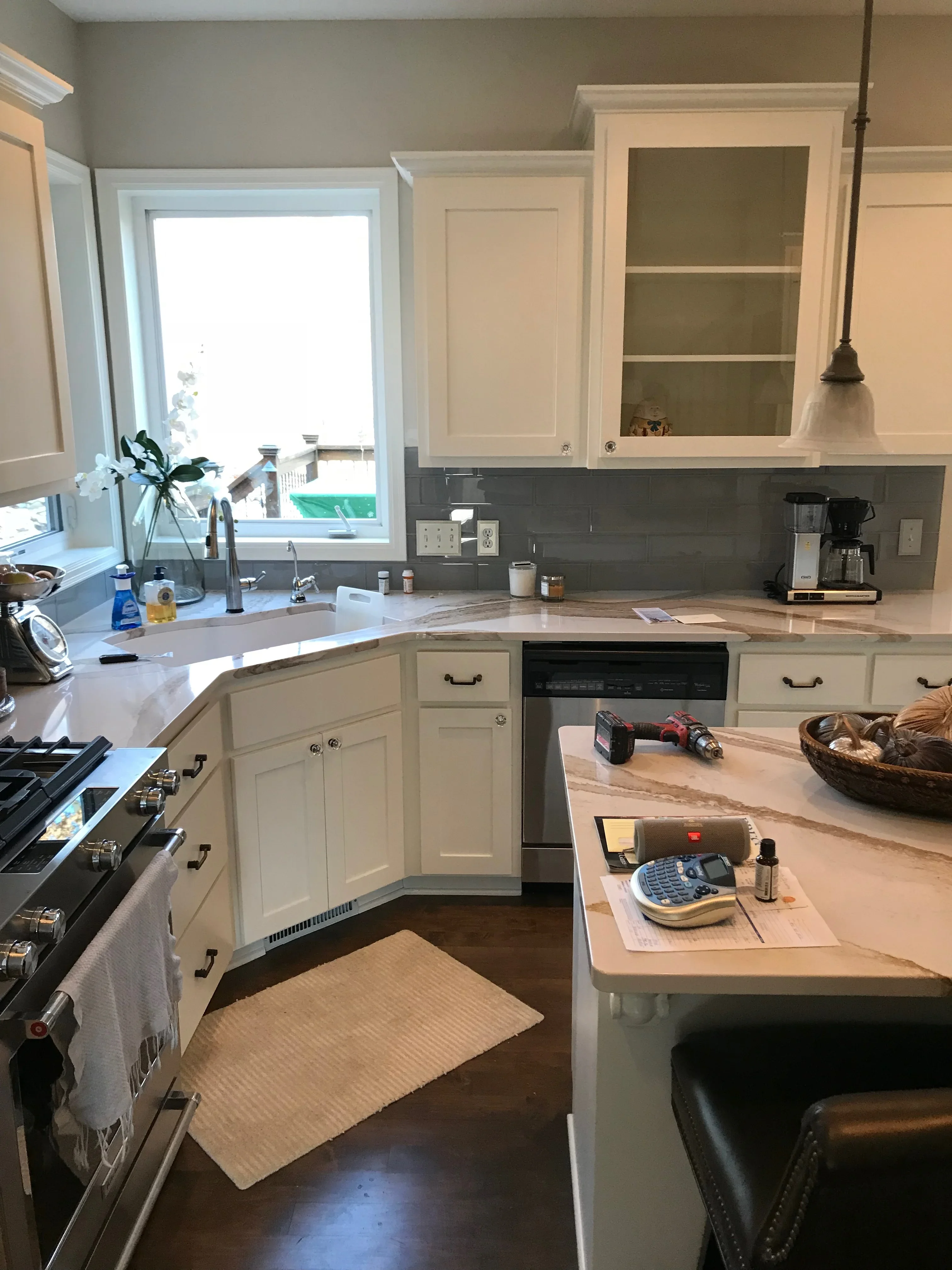 Cream painted kitchen cabinets with dark backsplash, white trim, and gray walls
