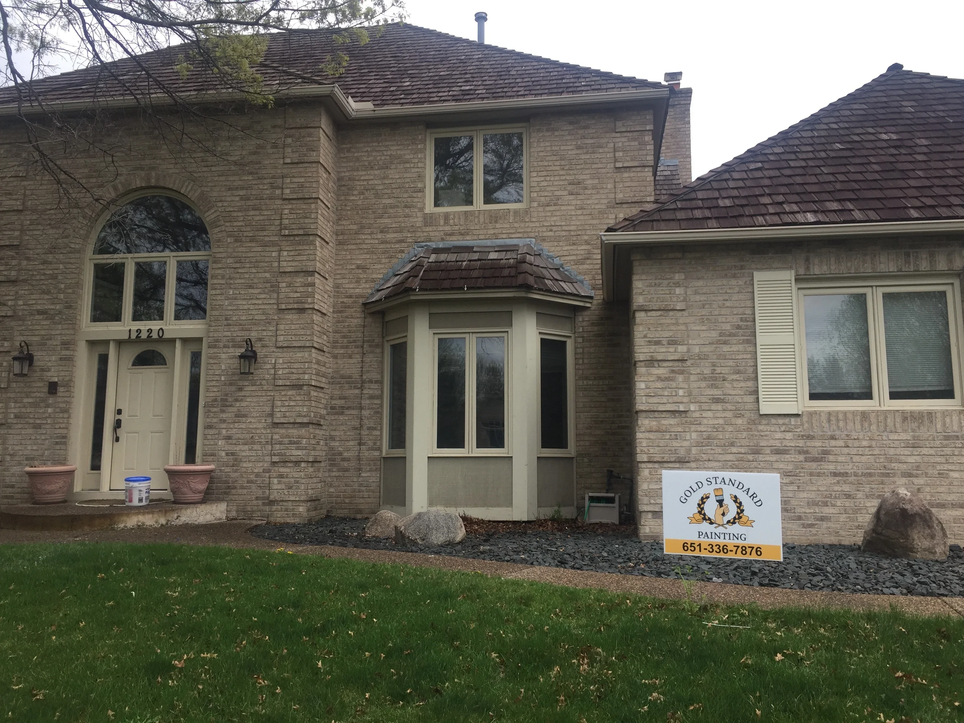 Two-story brick home with painted cream entry door, turret, and trim work