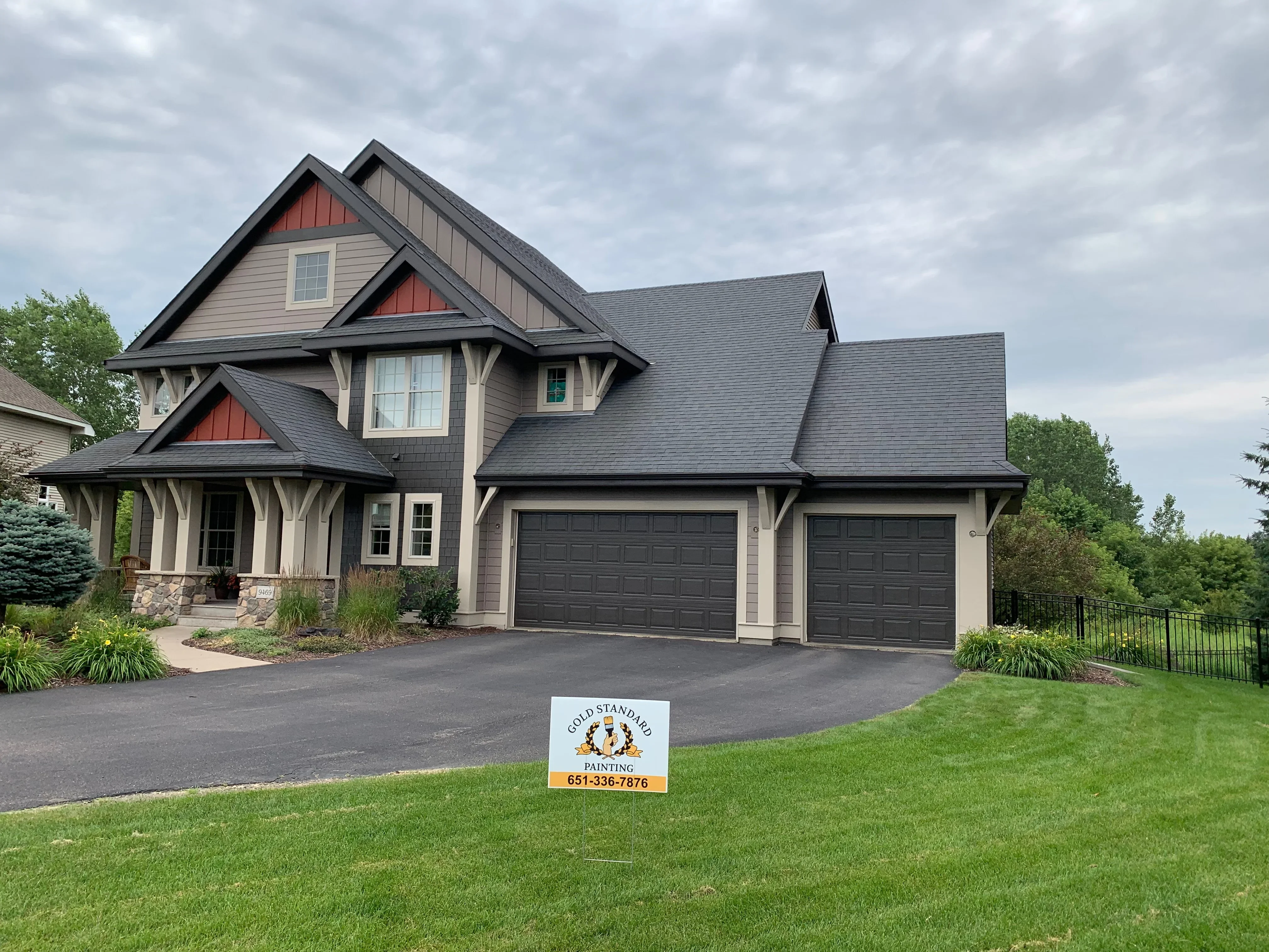 Two-story craftsman home with taupe siding, red gable accents, charcoal roof, and painted trim details