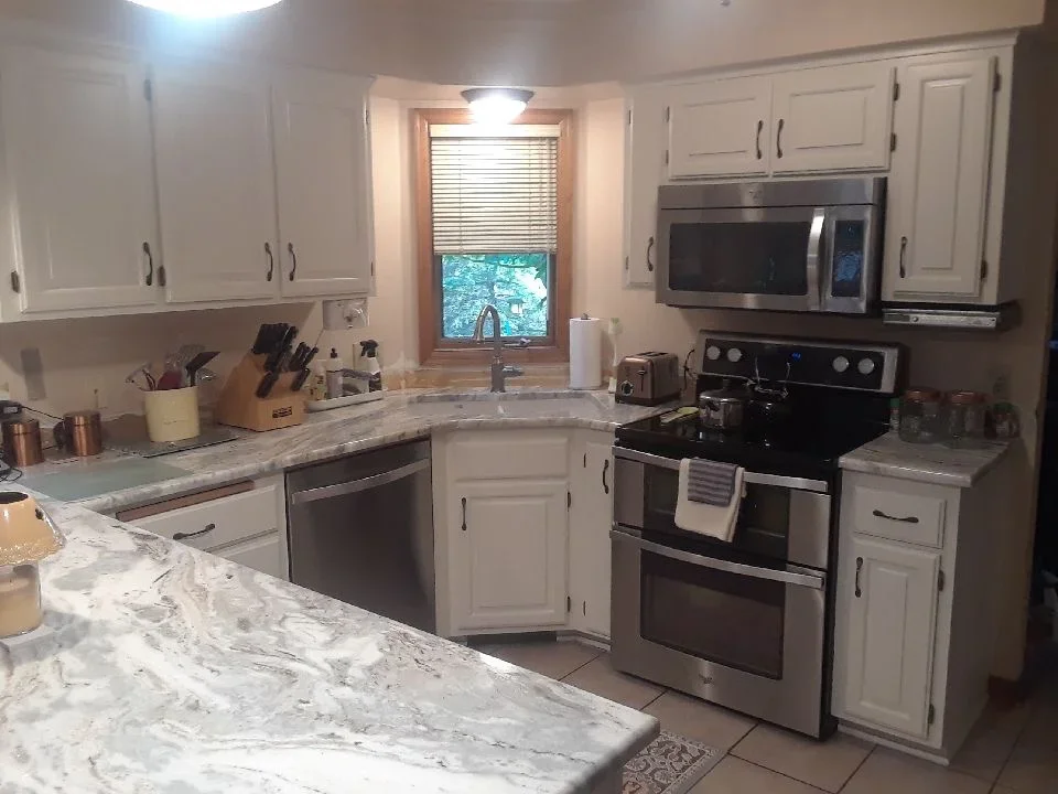 White painted kitchen cabinets with stainless steel appliances and granite countertops