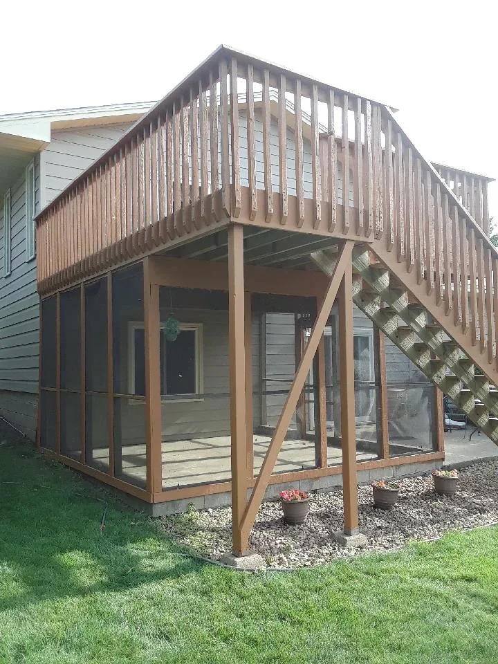 Two-story wood deck with stained railings, posts, and integrated staircase on residential home