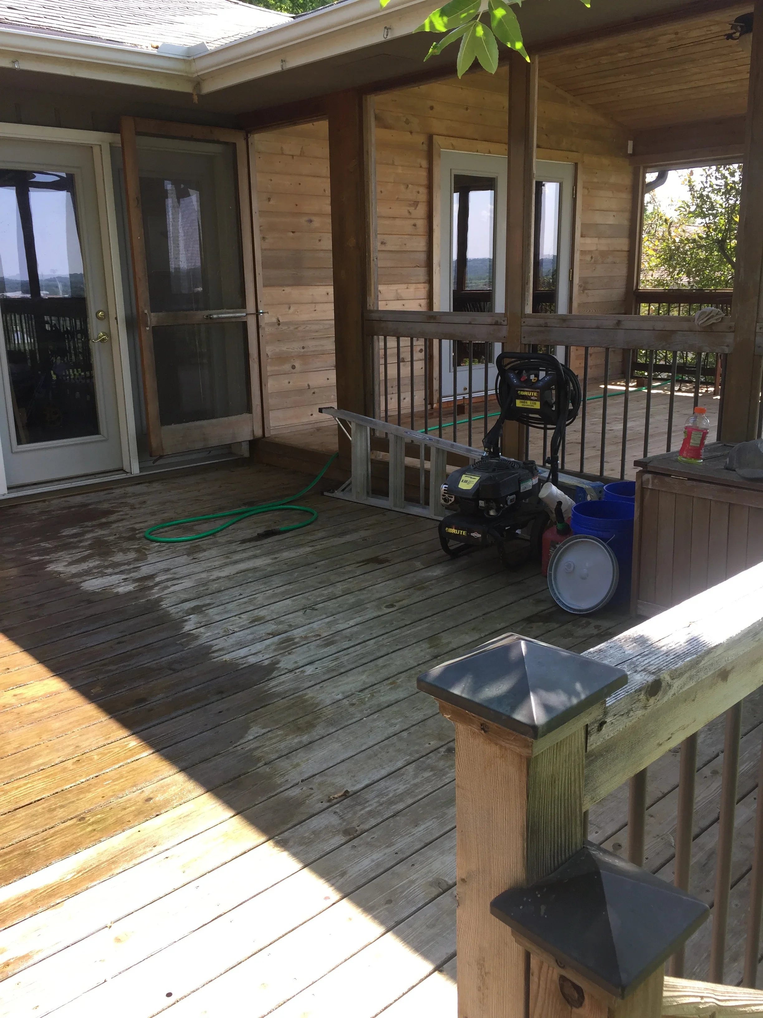 Pressure washer on composite deck with cedar siding and railing during cleaning preparation