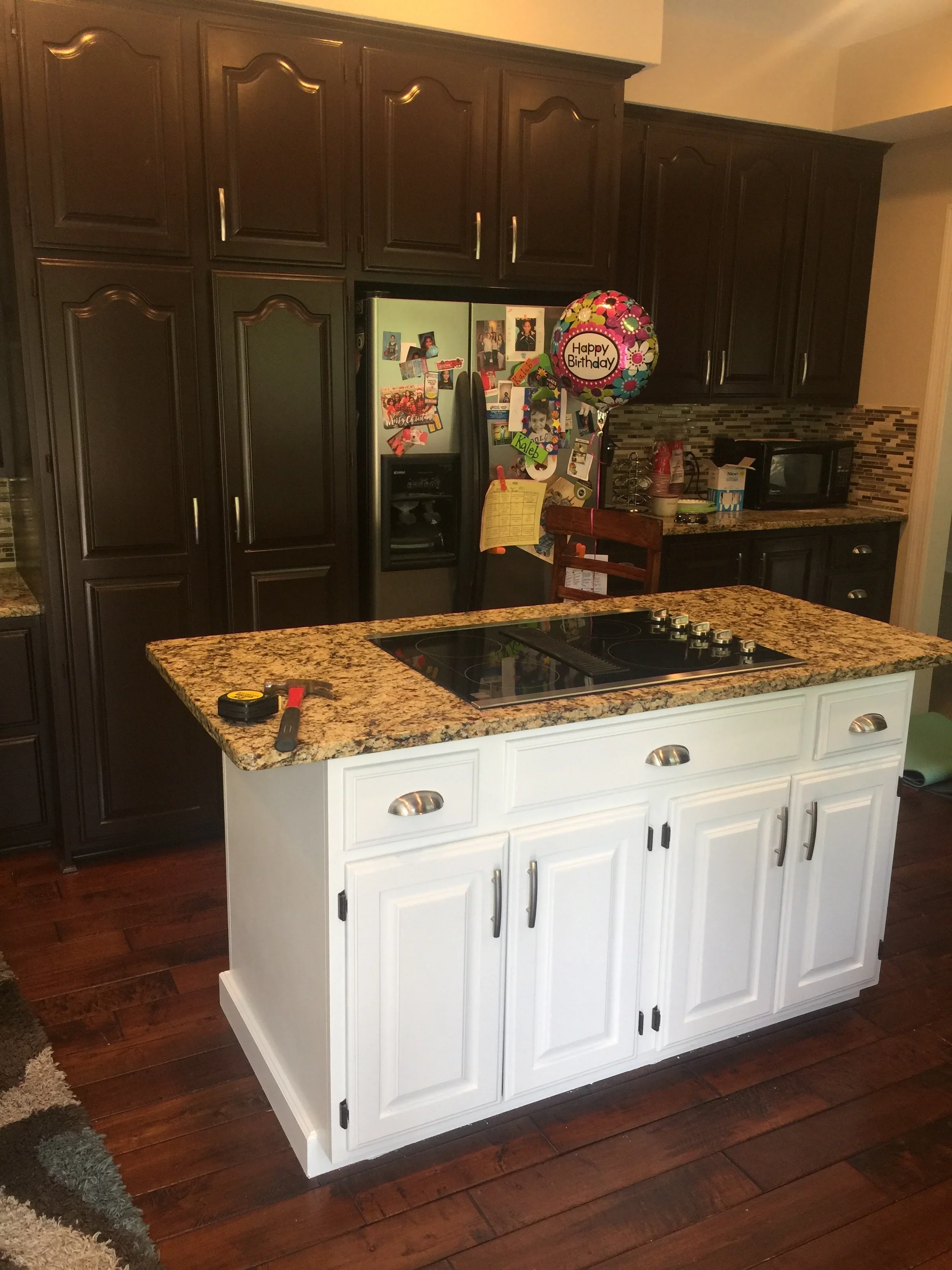Dark espresso and white painted kitchen cabinets with granite countertop and island