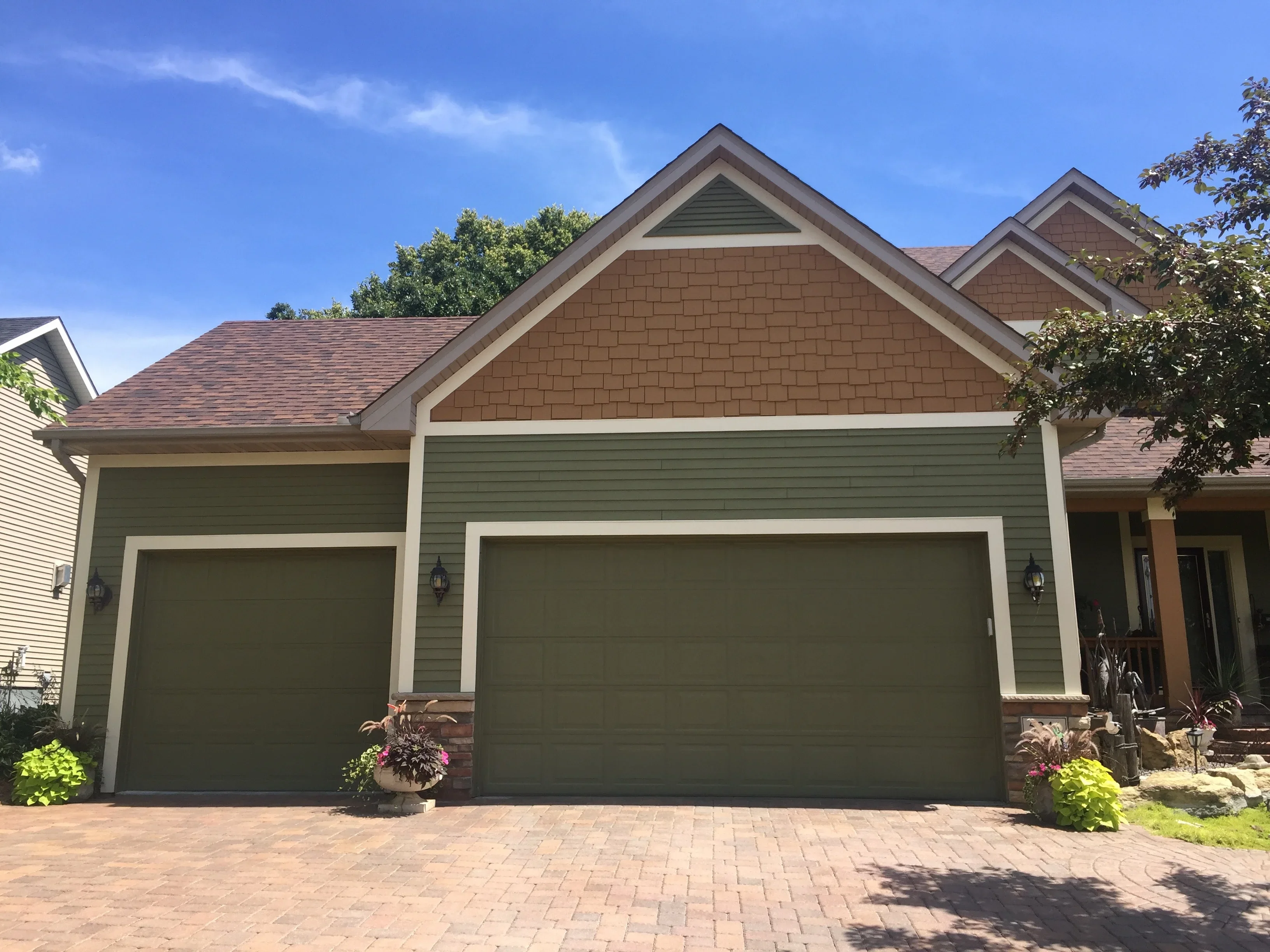 Sage green vinyl siding with white trim and brown cedar shake shingles on residential garage and home exterior