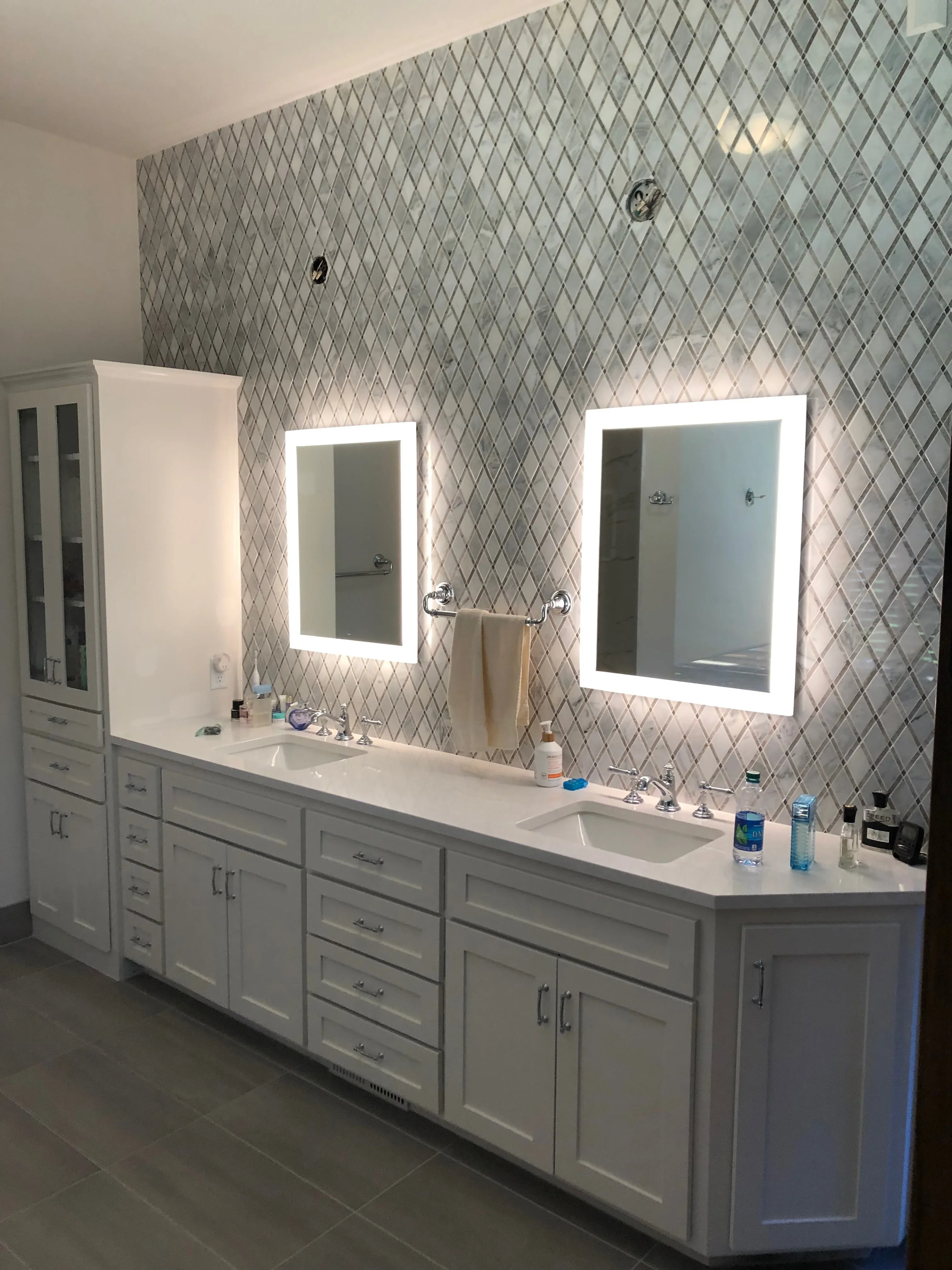 Geometric wallpaper feature wall with two lit vanity mirrors and dual white sink vanity