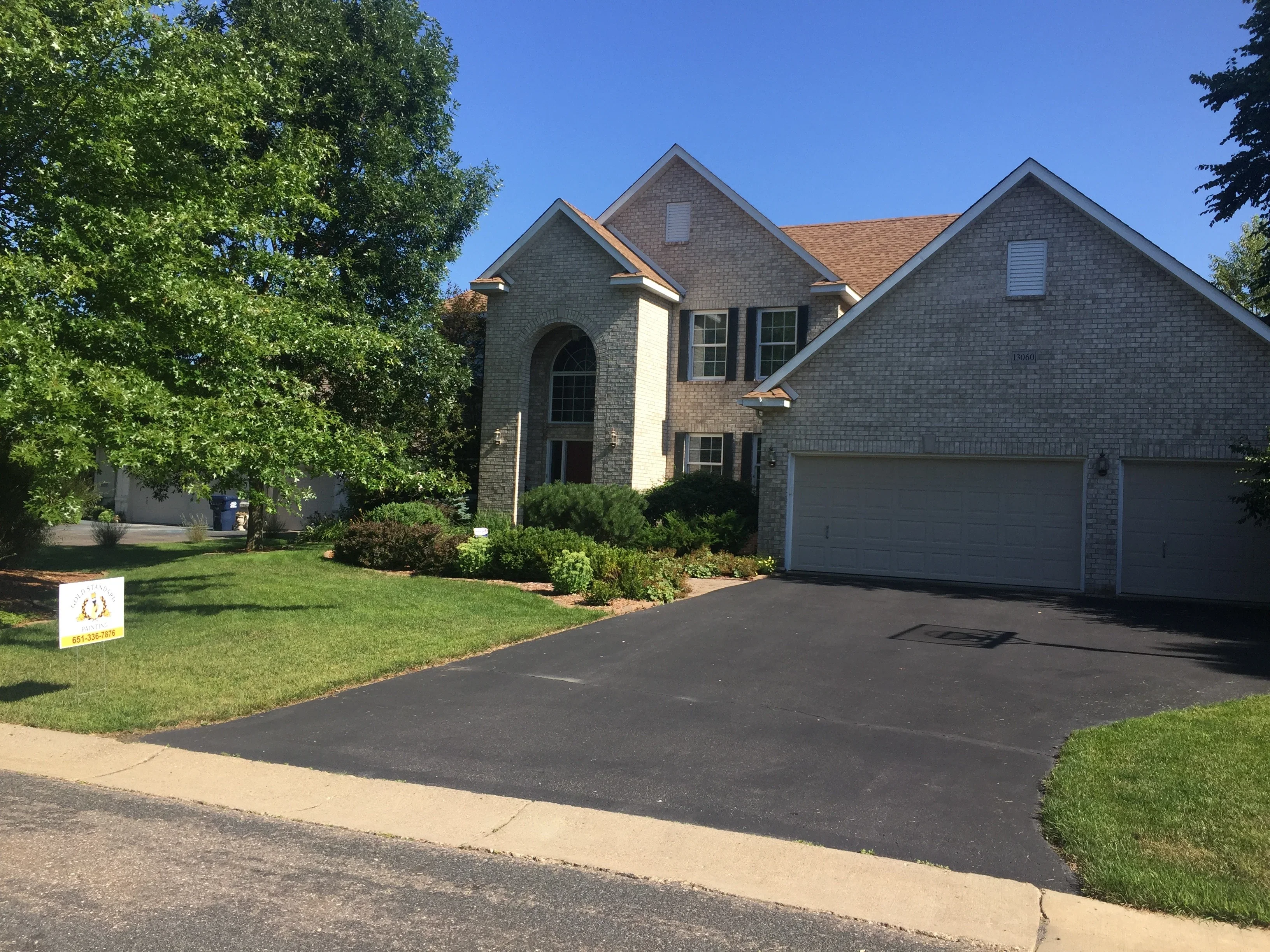 Two-story brick home with painted trim, soffits, and fascia; asphalt driveway